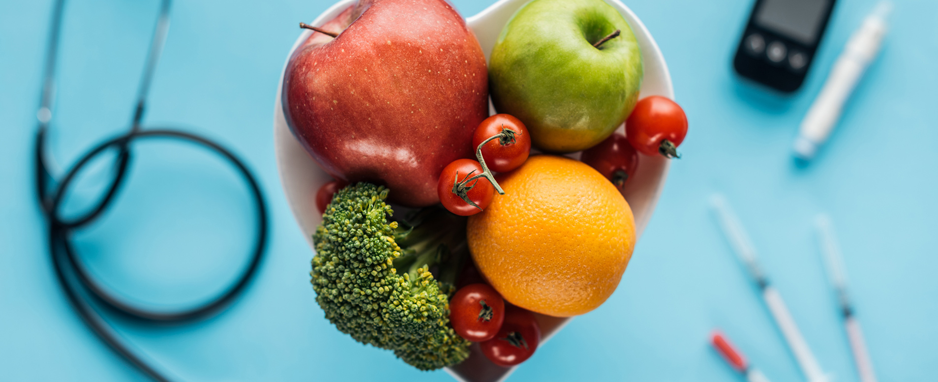 A bowl of fruit for a healthy diet with medical diabetes support devices in the background