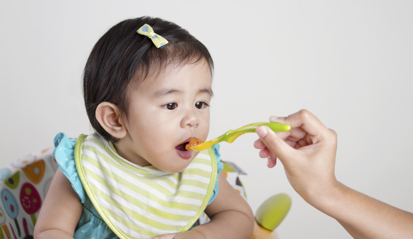 Baby being fed solid food