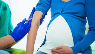 Pregnant person receiving a shot from a healthcare professional