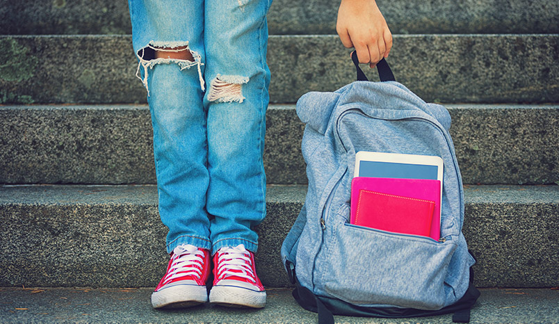 child holding backpack on stairs