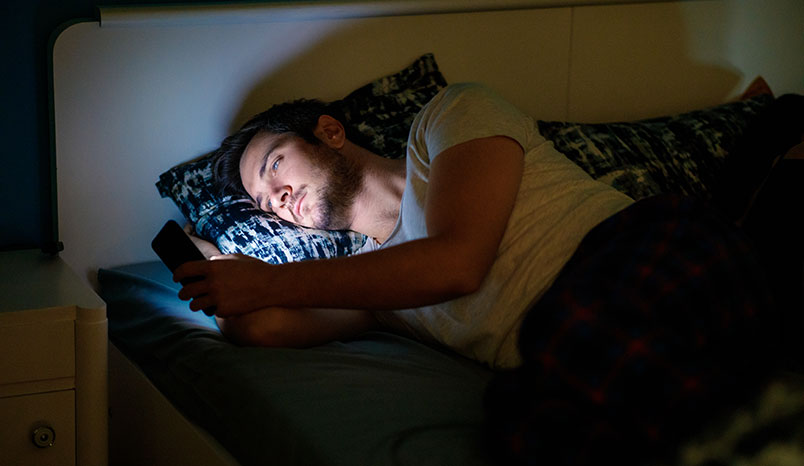 man-staring-at-smartphone-in-bed