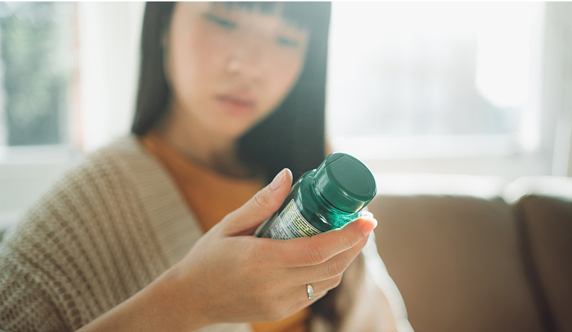 Hand-holding-bottle-containing-dietary-supplements