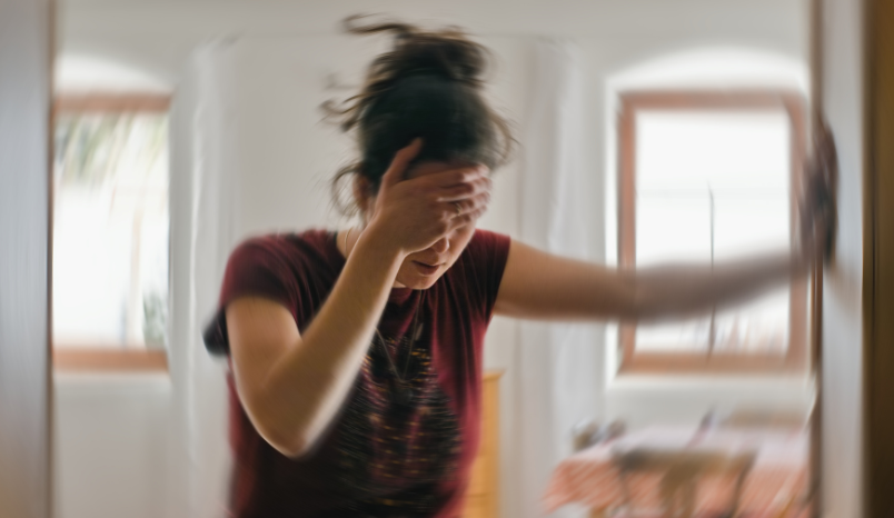 Person with hand against wall and appearing dizzy.