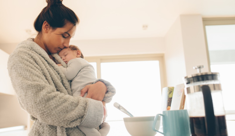 Woman in bathrobe holds newborn.