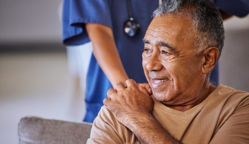 Older man holds the hand of a nurse.