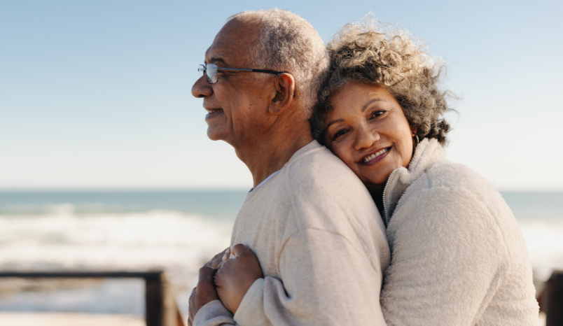 Older adults embracing on a beach.