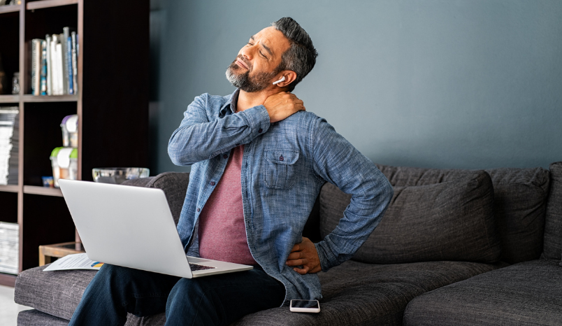 Man using laptop holds neck in pain.