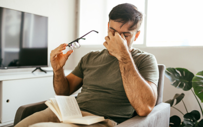 Man with headache takes off glasses and rubs his eyes.