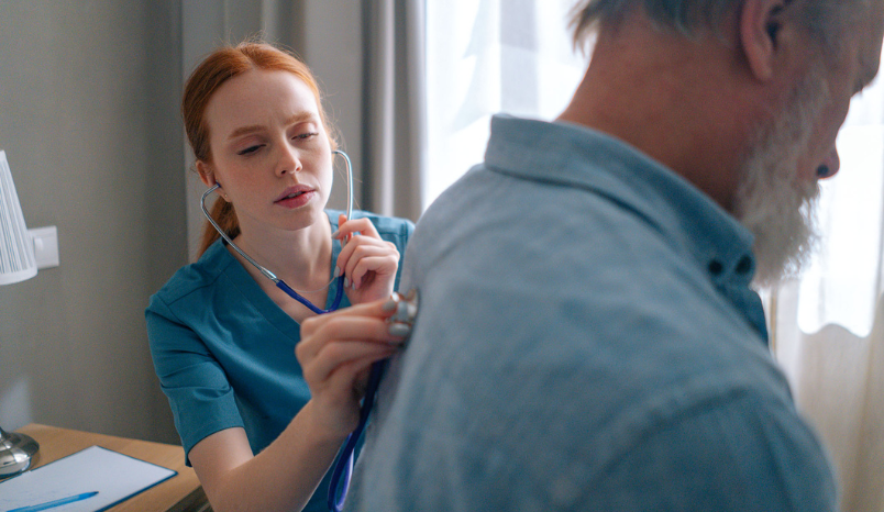 Nurse listens to man's lungs.