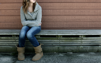 Young girl sits alone on bench.