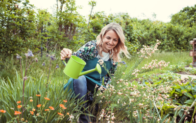 Woman waters flowers in garden.