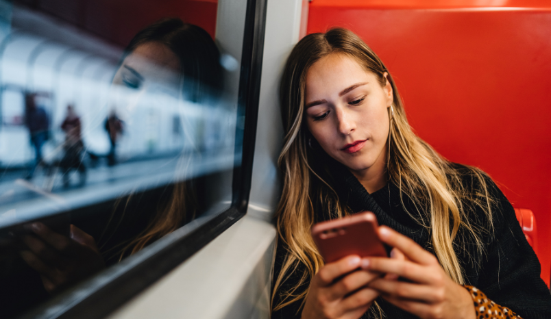 Girl on subway looks at phone.