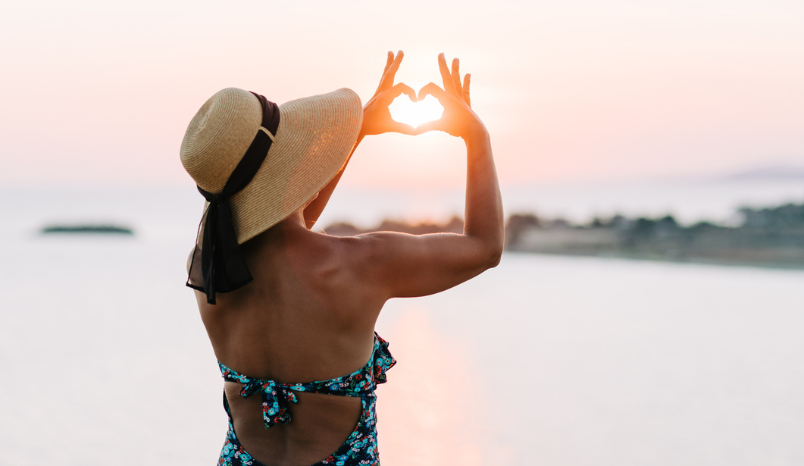 Woman in sun hat looks at sunset.