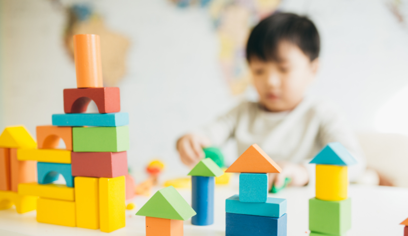 Toy building blocks sit on table with child in the background.