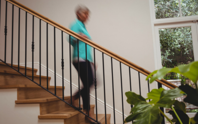 Senior woman walks down stairs in her home.