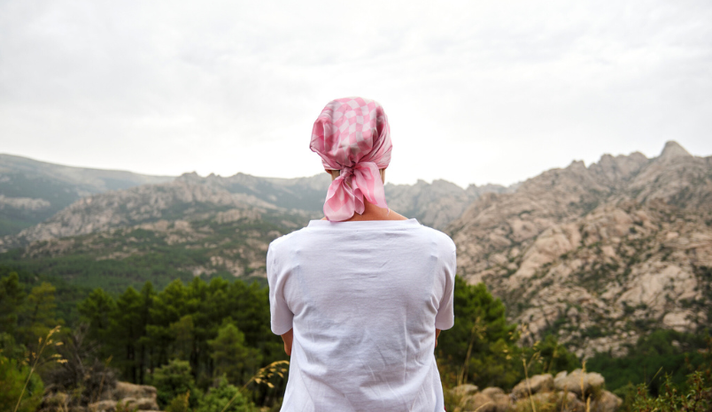 Cancer patient outside looking at mountain landscape.