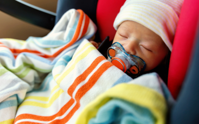 Infant in car seat with warm hat and blanket.