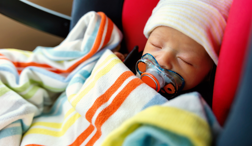 Baby in car seat with warm hat and blanket.