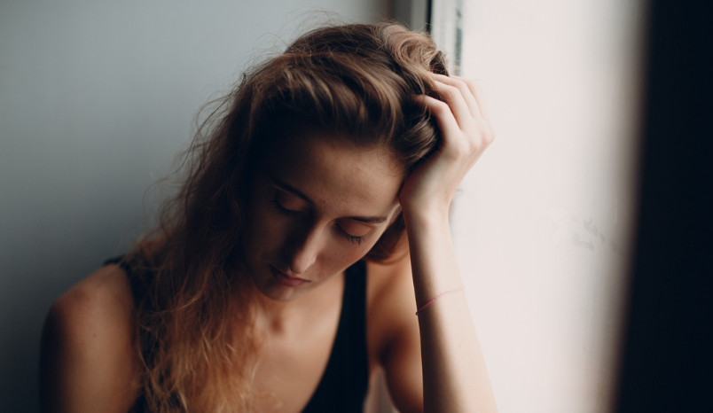 Woman runs hand through hair, appears distressed.