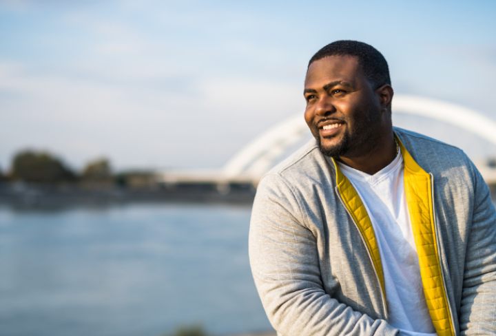 Man sitting by water looks off into the distance.