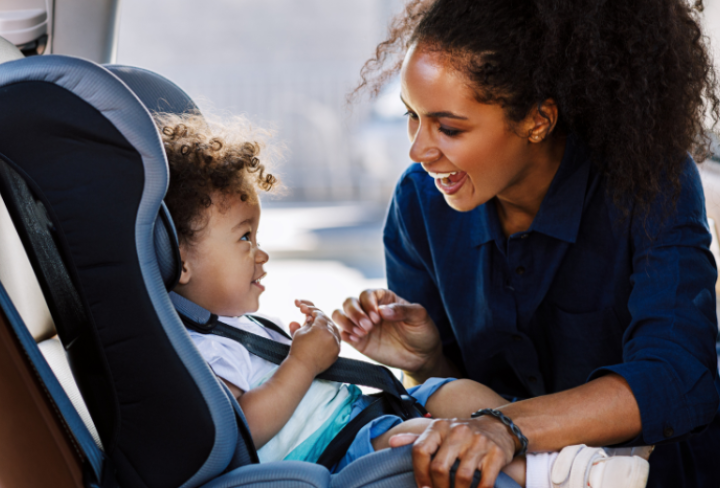 Mom puts baby in car seat.